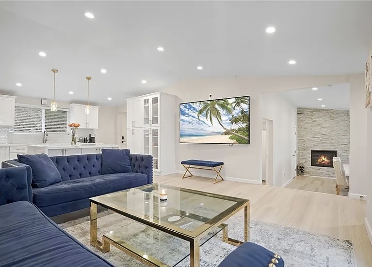 Open-plan luxury living room with blue velvet sofas and fireplace